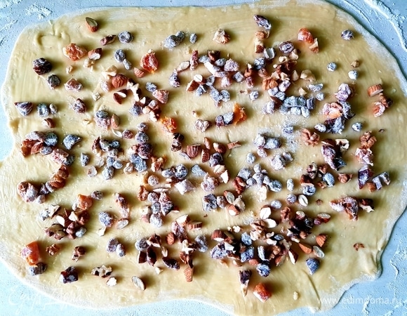 Сливочное масло растопить. Тесто разделить на 3 части. Каждую часть раскатать в прямоугольник размером примерно 30х40 см. Смазать маслом. Сухофрукты обвалять в муке и разделить на 3 части. Орехи порубить ножом и тоже разделить на 3 части. На раскатанное тесто выложить одну часть сухофруктов и орехов.