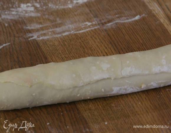 Смазать тесто шоколадно-ореховой пастой, отступая от краев на 1‒2 см, посыпать орехами с апельсиновой цедрой и свернуть в рулет почти до конца, оставшийся край теста смазать предварительно размягченным сливочным маслом и скрепить его с рулетом.