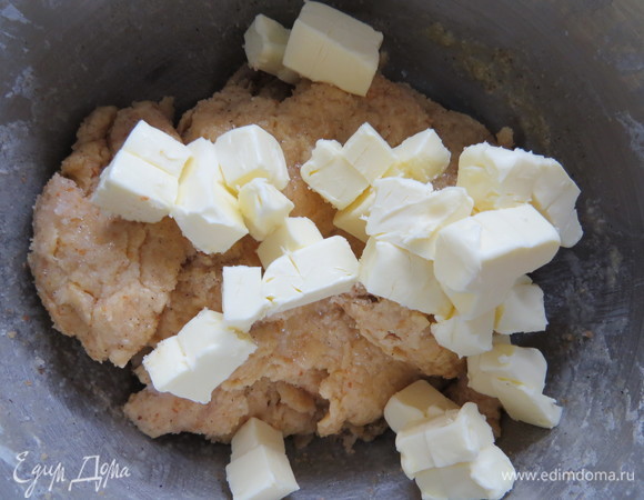 Ввести сливки, перемешивать до тех пор, пока тесто не впитает всю жидкость. Уменьшить обороты миксера и ввести половину сливочного масла.