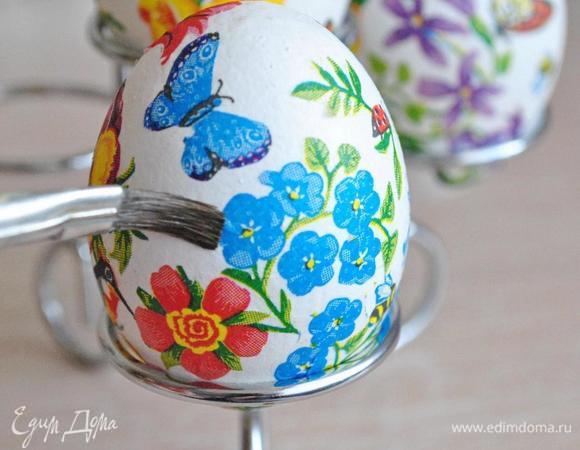 Картинки разложить на поверхности. Для удобства можно поставить яичко на подставку. Наложить выбранный фрагмент рисунка на яйцо и кисточкой, смоченной в яичном белке, провести поверх рисунка. Таким образом рисунок разглаживается и приклеивается одновременно.