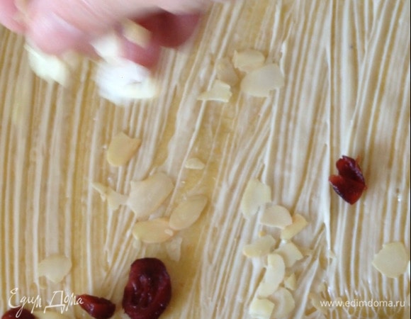 Посыпать сухофруктами, миндальными лепестками, скатать в рулет. Разрезать рулет вдоль, отступив от начала пару сантиметров. Закрутить улиткой одну половину рулета к началу, вторую половину закрутить, поднимая и укладывая поверх первой.