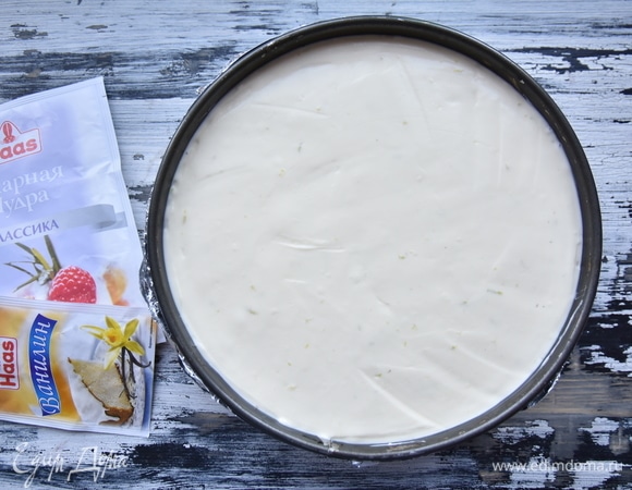 Бока и дно формы с остывшей основой обернуть несколькими слоями фольги. Выложить начинку. Постучать формой о рабочую поверхность, чтобы масса равномерно распределилась без воздушных пустот. Форму поставить в емкость большего диаметра с горячей водой. Выпекать чизкейк на водяной бане в духовке, разогретой до 160°C, 1 час 20 минут. Дать чизкейку полностью остыть, обернуть его пищевой пленкой и оставить часов на 8–10 в прохладном месте. Перед подачей освободить десерт от формы и украсить по желанию.