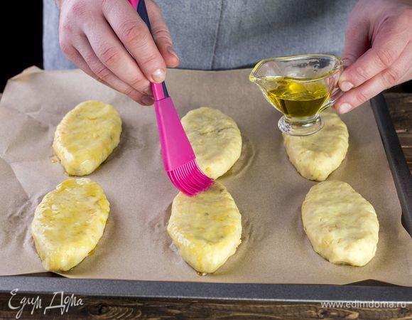 Выложите картофельные зразы на противень, застеленный пергаментом, сверху смажьте зразы маслом.