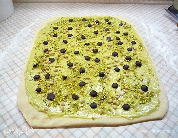 Раскатываем в пласт (примерно 20х30 см), смазываем тесто кремом, посыпаем кедровыми орешками, измельченными фисташками, посыпаем шоколадом. Можно по своему вкусу использовать любимые специи и добавки, не жалейте начинки, ведь пасхальная выпечка должна быть очень ароматной и вкусной!