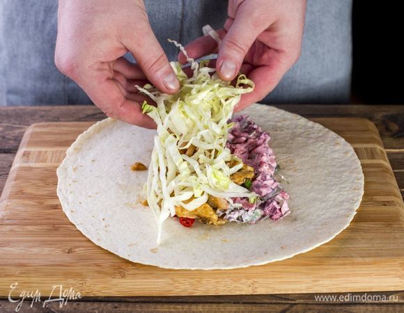 В центр лаваша выложите овощную начинку из капусты и отваренных вегенсов, сметану и куриное филе.