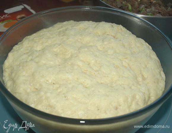 Через час тесто увеличится в объеме. Рабочую поверхность посыпать мукой и выложить на нее тесто. Обмять тесто руками.