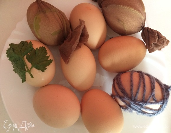 Далее включаем фантазию и берем различные природные и не природные материалы, накладываем их на яйца, я выложила листики укропа, петрушки, даже корешки от пророщенного лука, некоторые обмотала ниточкой, какие то обсыпала маленькими кружочками типа конфетти и т.д., и далее заворачиваем в капрон, завязываем нитью.