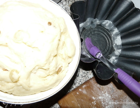 Перемешать основные ингредиенты основательно, так чтобы масса была однородная. Далее начинам добавлять муку и продолжаем месить тесто до полного отлипания от руки. Мешать тесто обязательно вручную. Когда тесто превратится в однородную массу, добавляем туда изюм (можно растолченные орехи или цукаты). Все перемешали и снова положили в емкость доходить на 30–40 минут в теплое место, предварительно закрыв. Приготавливаем форму, обильно смазываем подсолнечным растительным маслом, а на дно кладем кружок из пергамента. Заполняем форму на 2/3 тестом.