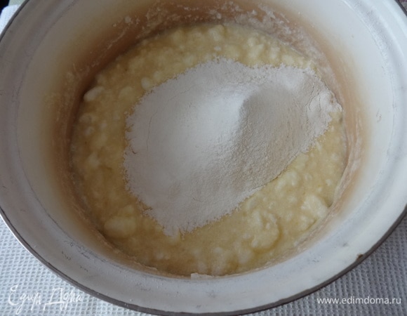Порциями всыпать муку и замесить тесто. Сначала мешать ложкой, затем по мере увеличения количества муки — руками.