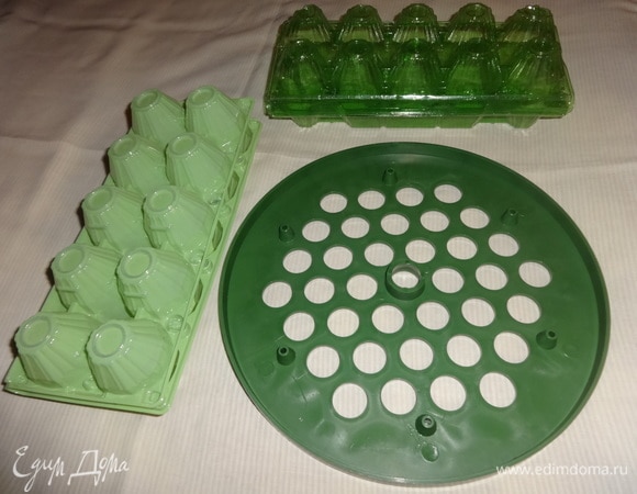 Для изготовления подставки мне понадобились: пластмассовая пельменница зеленого цвета, пластиковые упаковки из-под яиц (желательно зеленого цвета), разноцветные атласные ленты разной ширины, иголка с нитками в тон лент, универсальный клей, ножницы. Для основы также можно использовать картон или дерево, покрашенное в зеленый цвет. Для ячеек можно взять картонные упаковки для яиц и тоже покрасить их в зеленый цвет.