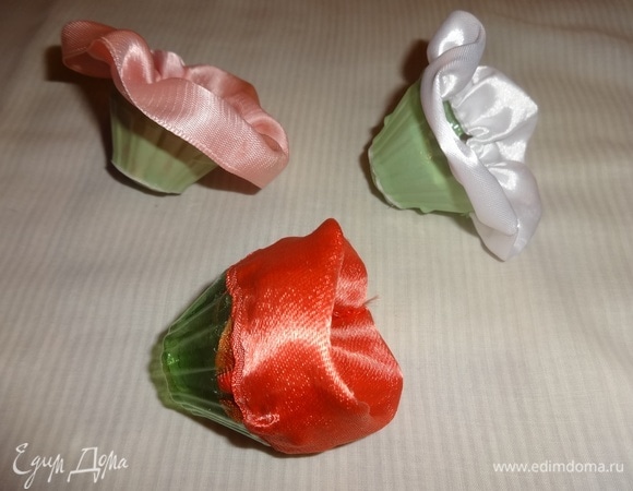 Из разноцветных атласных лент вырезать полоски длиной в 1,5–2 раза больше диаметра круглых ячеек. Сшить концы полосок и присобрать, формируя цветы. Приклеить атласные цветы к ячейкам универсальным клеем.