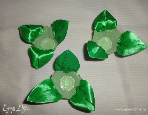 Из зеленой атласной ленты сделать листья и приклеить их в 3 круглые ячейки.