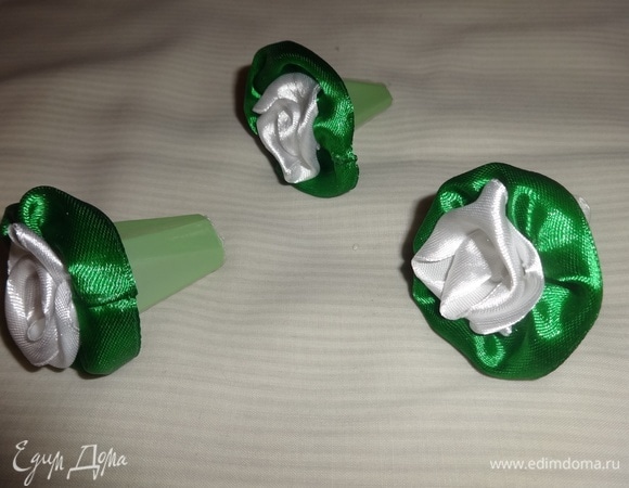 Из белых ленточек скрутить 3 розочки, из зеленых — основу. Вклеить основу и цветы в удлиненные ячейки.