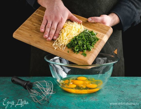 В миску разбейте яйца. Добавьте к яйцам зелень, тертый сыр и цедру, тщательно перемешайте.