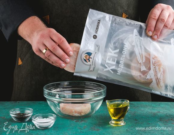 Разморозьте и промойте медальоны хека ТМ «Капитан Вкусов», добавьте соль, перец, оливковое масло.