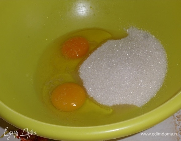 В другую чашку выкладываем куриные яйца и сахар. Слегка взбиваем.