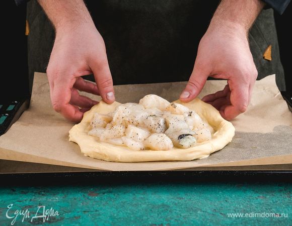 Часть теста разомните руками на противне в круг. В центр выложите рыбу.