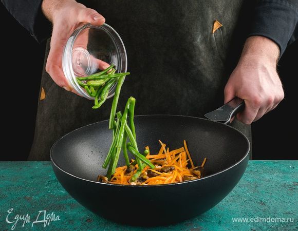 На сковороду с растительным маслом выложите шампиньоны, морковь и стручковую фасоль, обжарьте в течение нескольких минут.