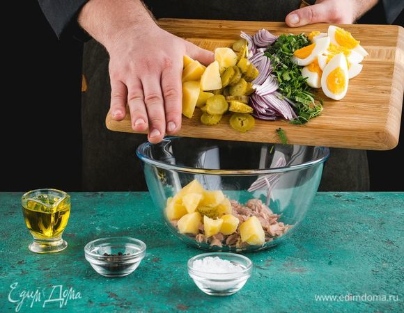Отварите картофель и яйца до готовности, нарежьте кубиками. Также нарежьте маринованные огурцы и красный лук. Измельчите укроп и петрушку. Добавьте к тунцу все ингредиенты.