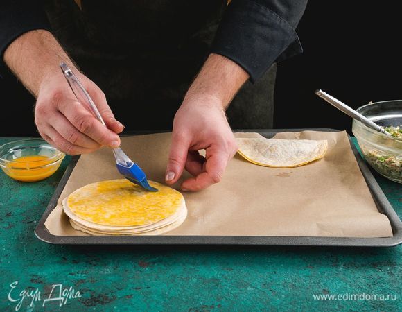 Выложите заготовки на противень, смажьте желтком.