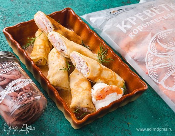 Трубочки из блинов нарежьте на порции и выложите на тарелку. Вкусные блинчики с морепродуктами готовы. Приятного аппетита!