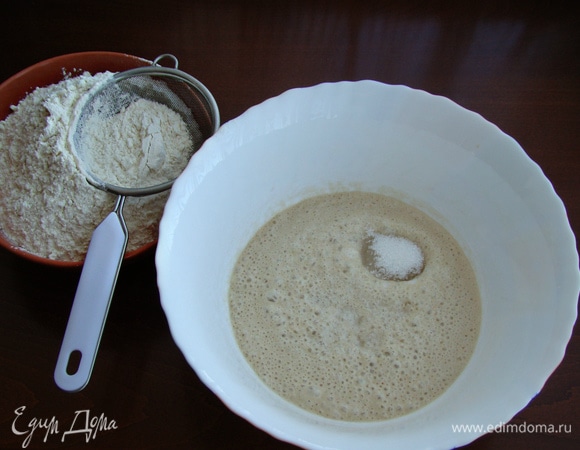 Перелить дрожжи в миску, влить остальную часть теплой воды, смешанной с 0,5 ч. л. соли, добавить сахар и частями всыпать муку.