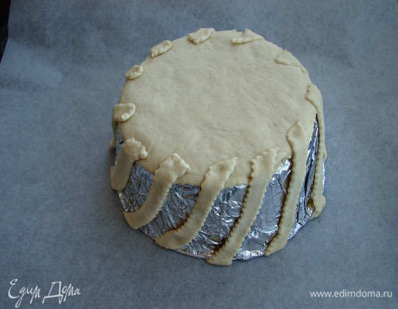 Подошедшее тесто обмять, раскатать в пласт толщиной 0,5 см и сначала вырезать два круга диаметром, равным дну формы нашей чаши. Оставшееся тесто нарезать на полоски шириной в 1 см. Сначала на чашу положить один круг. К нему прикрепить полоски, уложенные по кругу наискосок.