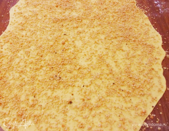 Тонко раскатать тесто в овал (у меня около 40х50 см) и посыпать поверхность орехами.