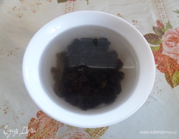 Изюм промываем водой, выкладываем в чашку, заливаем горячей водой и оставляем на 10–15 минут. Затем обсушиваем на полотенце.