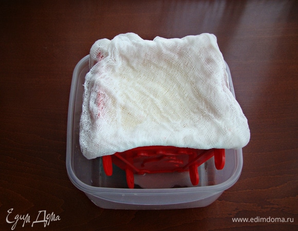 Края марли завернуть наверх. Сверху поставить гнет, а саму пасочницу поместить в емкость. Конструкцию поставить в холодильник на несколько часов, периодически сливая сыворотку.