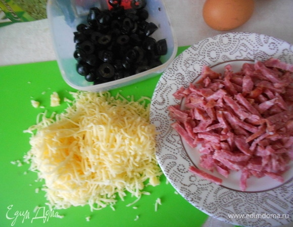 Приготовить ингредиенты для начинки. Сыр натереть на мелкой терке. Колбасу нарезать тонкими брусочками. Маслины нарезать кружочками.