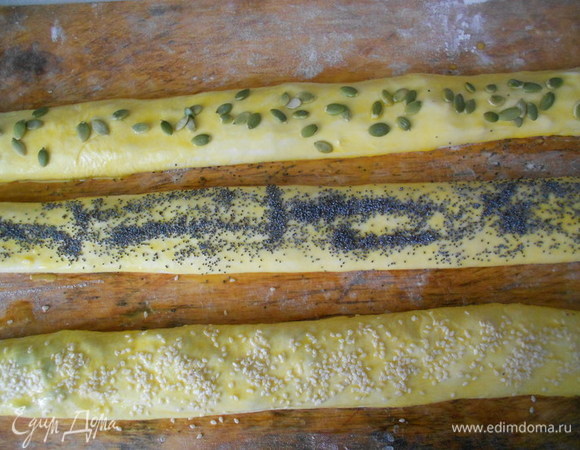 Аккуратно защипнуть края теста. Дать расстояться 10–15 минут. Каждую часть теста смазать взбитым яичным желтком и посыпать одну косу — кунжутом, вторую — маком, третью — тыквенными семечками.