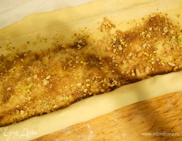 Подошедшее тесто раскатать в прямоугольный пласт толщиной 1 см. Смазать масляно-медовой начинкой, отступая от краев на 1 см. Сверху посыпать сухой начинкой, орехами и изюмом, свернуть в рулет.