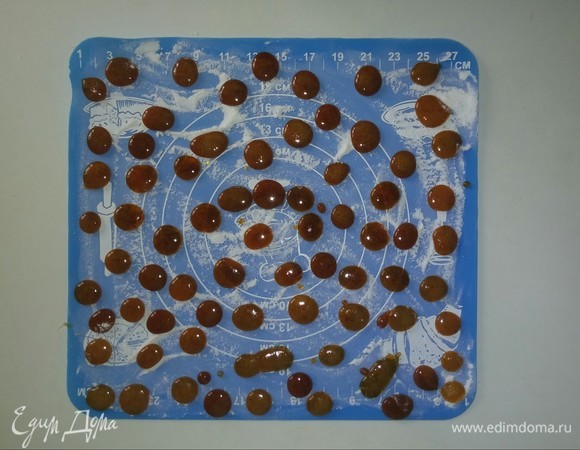 Выкладываем карамель чайной ложечкой, формируя небольшие кружочки. Карамелек получается достаточно много. Если в процессе выкладывания карамель в ковшике начинает остывать, и ее трудно будет выкладывать, то нужно поставить ковшик на пару секунд на огонь, помешать и снова карамель станет жидкой. Так как ковшик с толстым дном, то при выкладывании карамели держать его очень тяжело, я кладу рядом подставку под горячее, на которую ставлю ковшик.