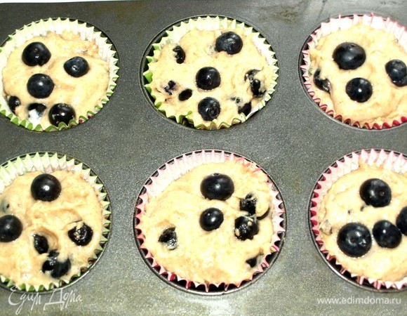 В формы для кексов ставим бумажную формочку и выкладываем в нее тесто. Сверху на тесто добавить несколько ягод голубики. Отправляем в духовку на 20 минут (ориентироваться на свою духовку). Готовность проверить бамбуковой палочкой.