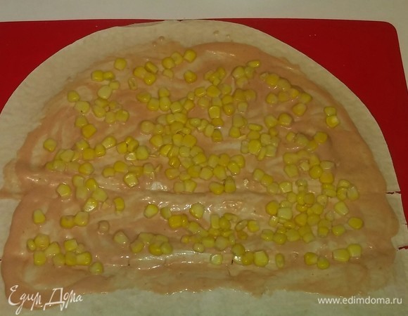 Затем выкладываем на соус часть кукурузы. Со второй частью лаваша поступаем так же.