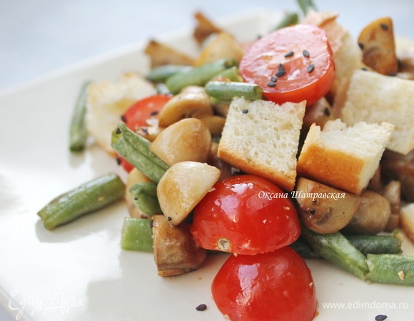 Добавить нарезанные пополам черри, сухарики, перемешать, сверху посыпать черным кунжутом и сразу подавать к столу.