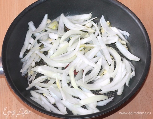 Репчатый лук, чеснок нарезать и выложить в сковороду с разогретым оливковым маслом, обжарить 1–2 минуты.