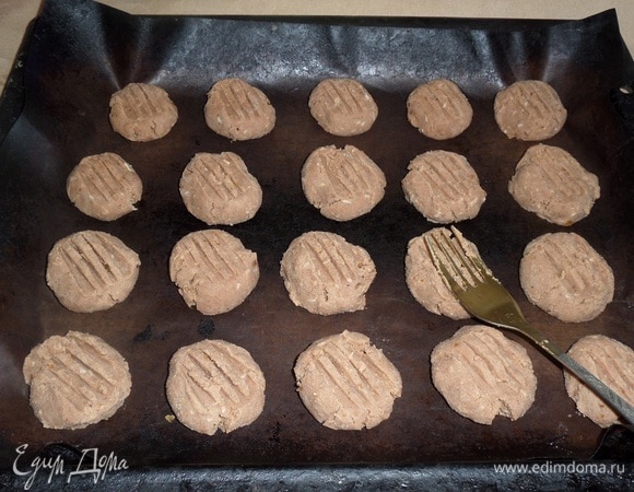 Выкладываем шарики теста на противень, застеленный пергаментом или антипригарным ковриком. Вилкой наносим рисунок на каждое печенье.