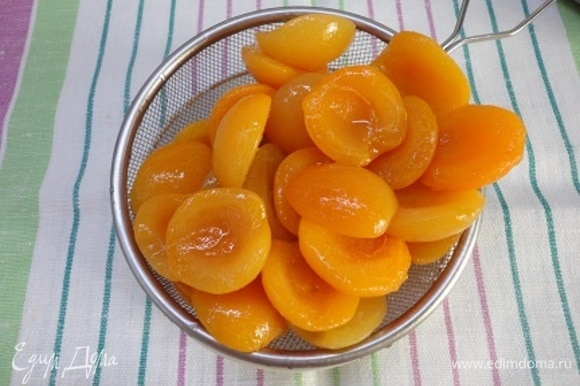 Пока бисквит остывает, откиньте половинки абрикосов на дуршлаг.