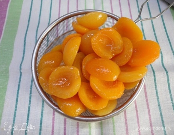 Пока бисквит остывает, откиньте половинки абрикосов на дуршлаг.