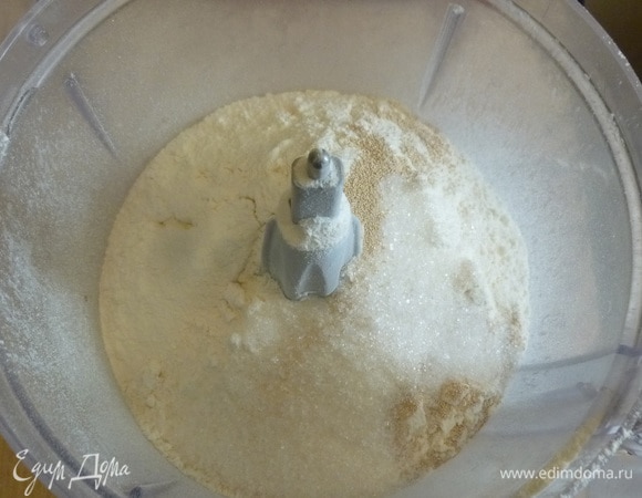 Для теста в чашу кухонного комбайна просеять муку, добавить дрожжи, сахар и ванильный сахар.