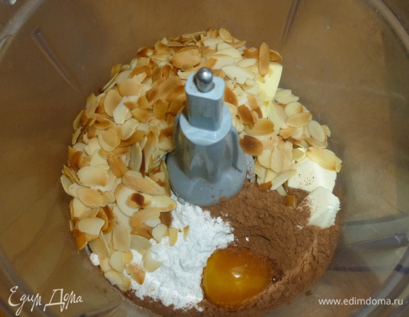 В чашу комбайна выложить подрумяненные лепестки, какао, сахарную пудру, миндальный и ромовый ароматизаторы, сливочное масло и желток. Перемешать.