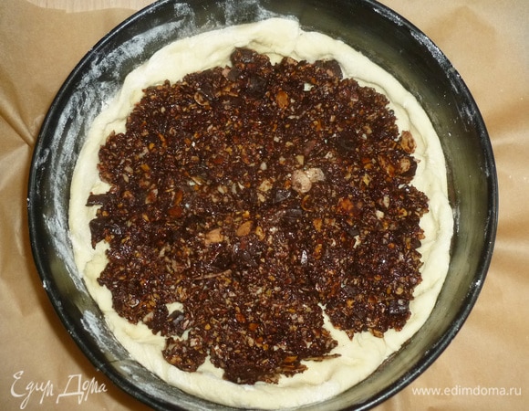 Форму (20–22 см) застелить пергаментом, бортики смазать маслом. Тесто разделить на две неравные части. Большую немного раскатать и выложить в форму, оставляя небольшие бортики. Распределить шоколадную начинку.