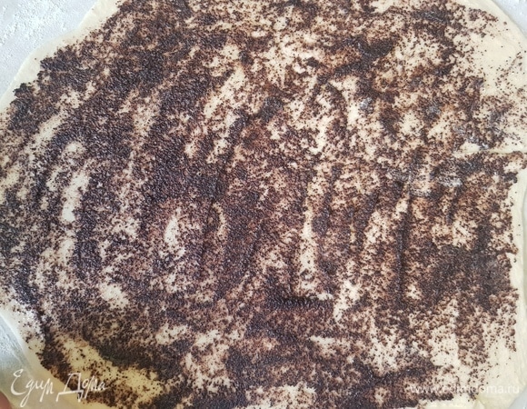 Одну часть выложить на посыпанную мукой поверхность и раскатать прямоугольник. Смазать сначала половиной растопленного сливочного масла, потом — половиной маковой начинки.