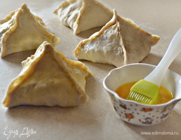 Приподнимите уголки теста каждого квадрата и соедините в центре, чтобы получилась пирамидка. Хорошо защипите края и смажьте взбитым яйцом.
