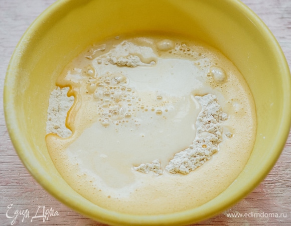 В мучной смеси сделать углубление. Влить туда теплое молоко и взбитые яйца с сахаром. Замесить тесто. Оно сначала будет очень липким. Продолжайте вымешивать.