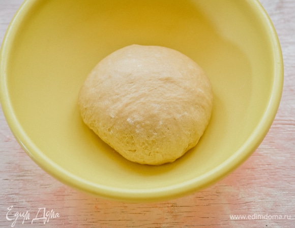 Смажьте большую миску сливочным маслом, положите тесто, накройте пищевой пленкой и поставьте на 1,5–2 часа в теплое место без сквозняков. Сухофрукты замочить в теплой воде на 15 минут. Откинуть на сито. Курагу и чернослив мелко нарезать. Обсушить.