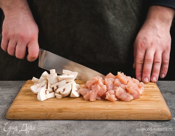 Куриное филе промойте, нарежьте небольшими кусочками, нарежьте шампиньоны крупными дольками.