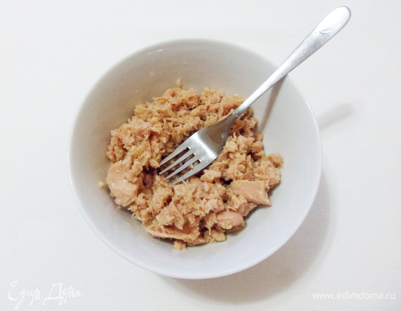 Консервированного тунца выложить в миску и размять вилкой.
